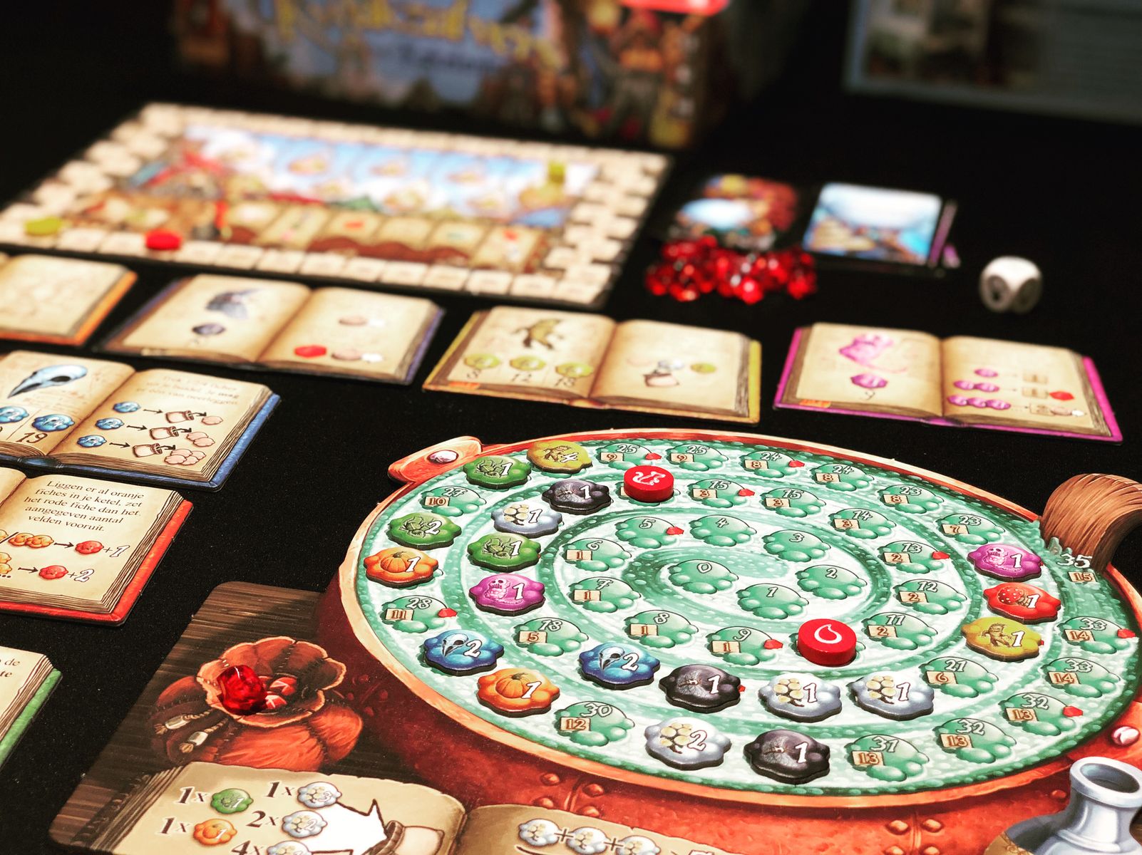cardboard books and a large cardboard pot (flat representation) are on a table.  Many colorful chips are on a swirly track in the pot 