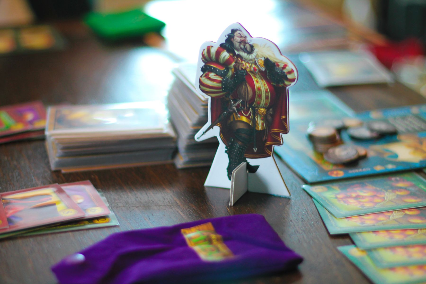 a snotty looking sheriff standee in a regal red and gold outfit stands on a table near a purple snap-lock bag and some cards