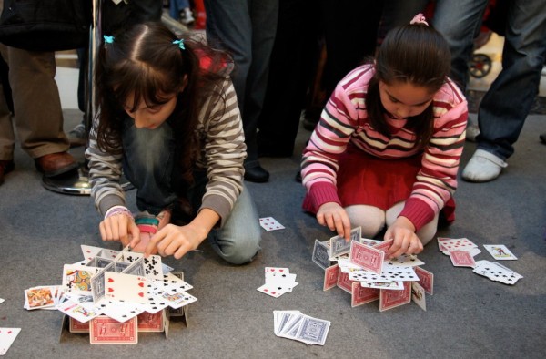 Two girls assembling their playing card structure.